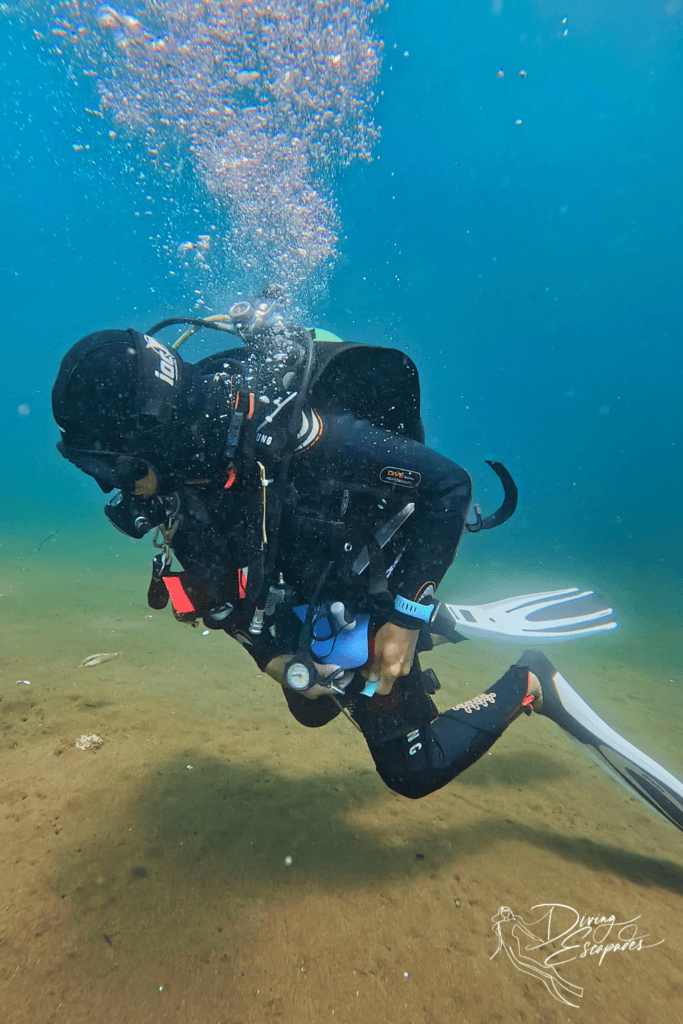 Dive Society Dauin divemaster picking up plastic and putting into TRSHBG